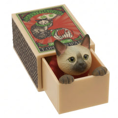 Siamese cat peeking out of its miniature matchbox