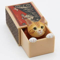 Orange tabby cat peeking out of its miniature matchbox